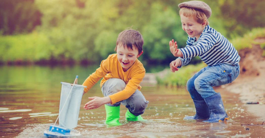 Kinder spielen mit Spielzeugboot am Wasser
