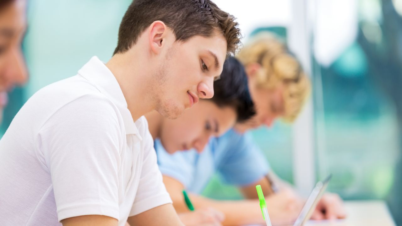 Drei Studierende in einem Unterrichtsraum.